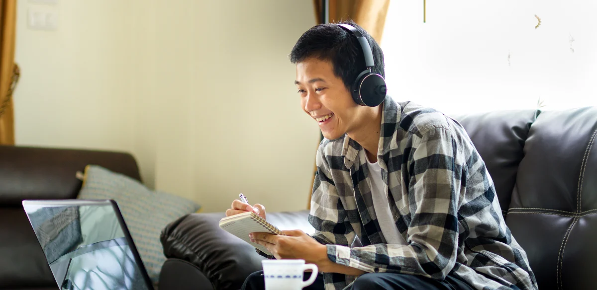 boy with headphones writing in the notebook