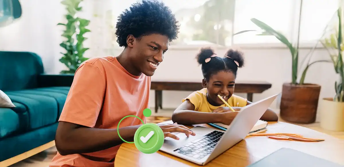 Man and young girl smiling while using a laptop together at a table.